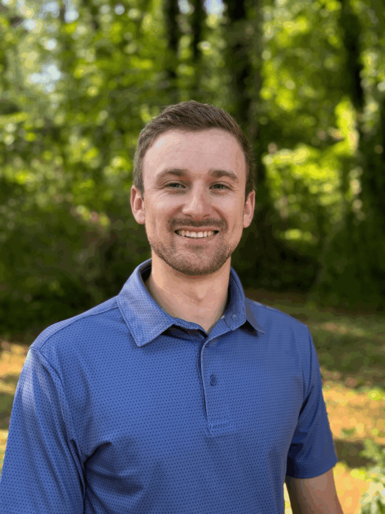Smiling person in blue shirt outdoors.