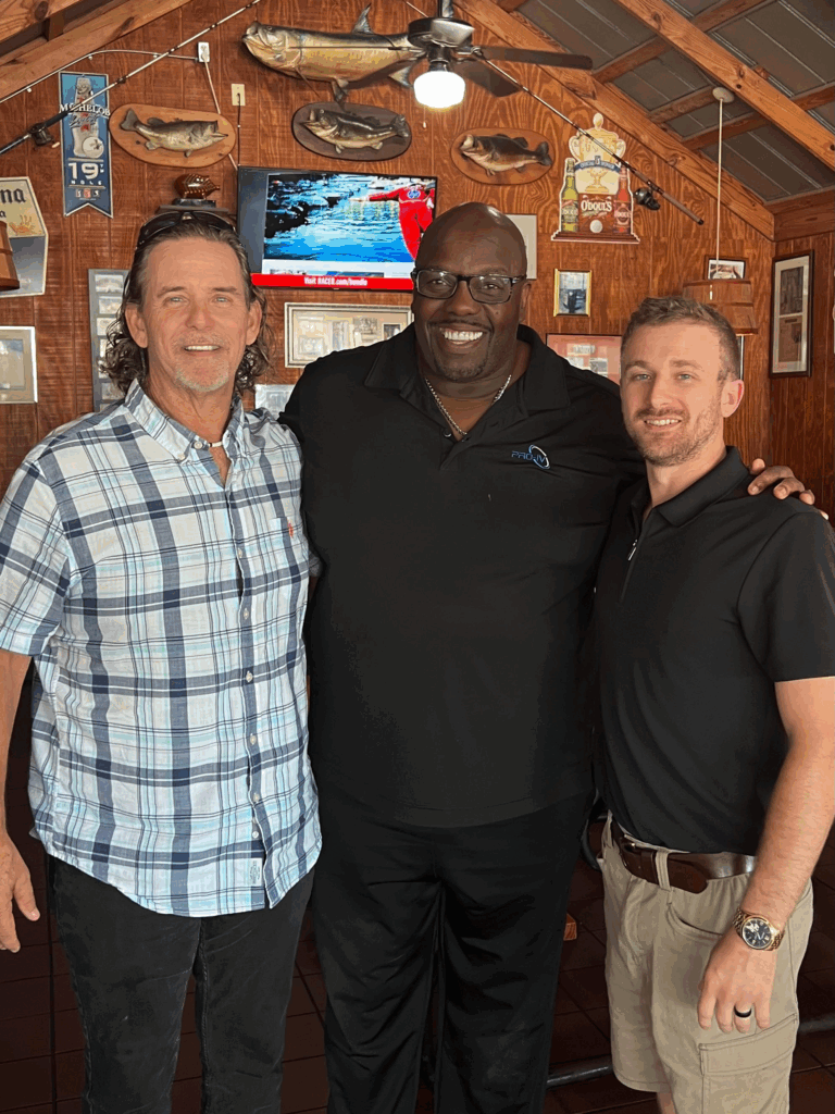 Three people smiling at a restaurant.