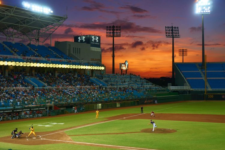 A vibrant baseball match in progress under stunning sunset skies in a crowded stadium.