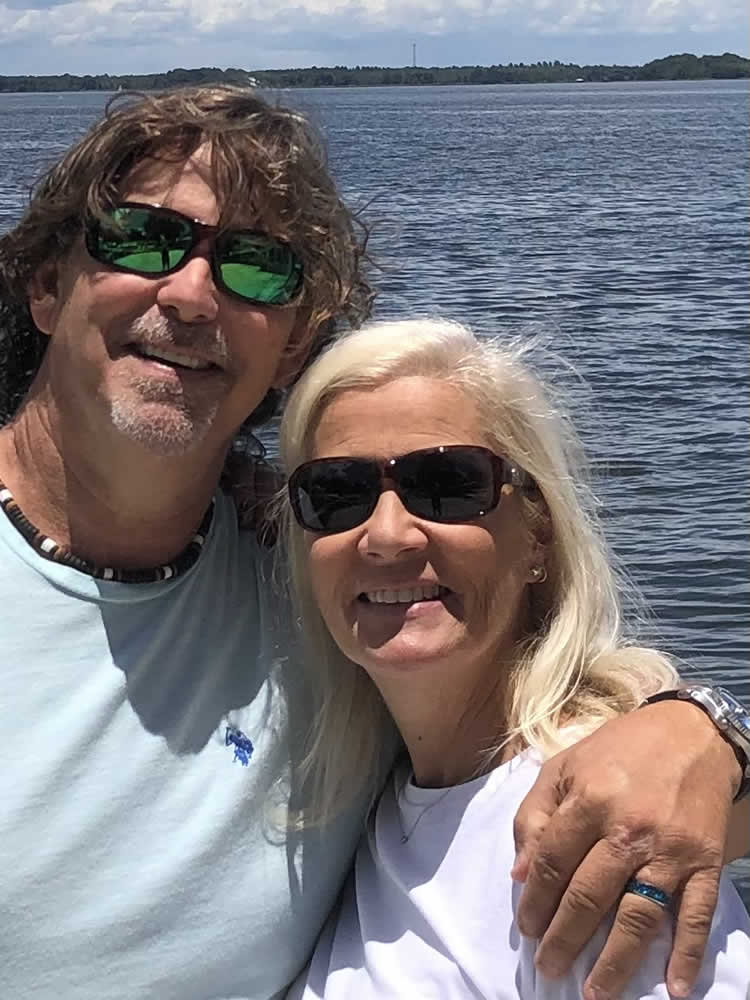 Couple smiling by the water on a sunny day.