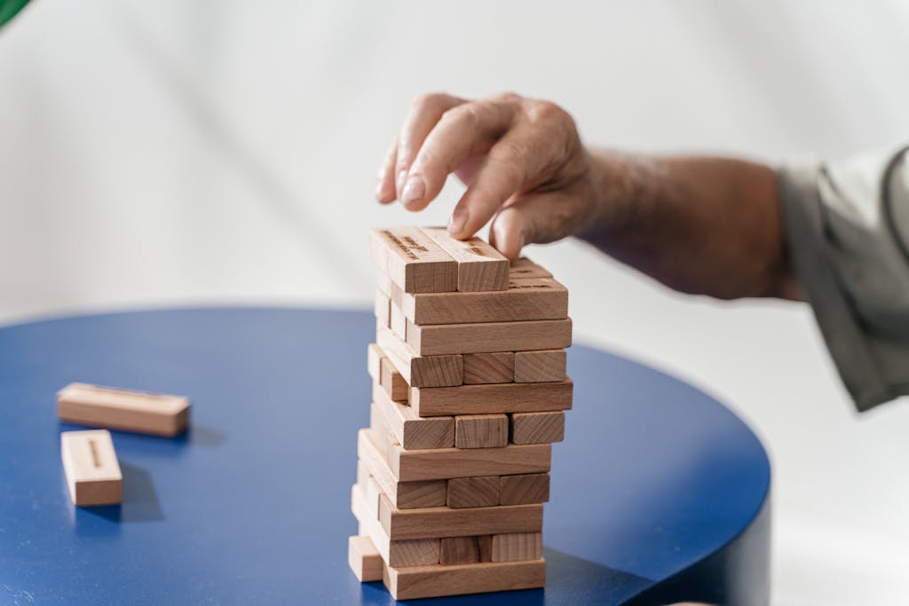 Close-up of a man's hand playing a game of Jenga, focusing on skill and precision.