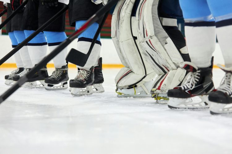 Focused view of hockey players' skates and sticks on an ice rink, ready for action.