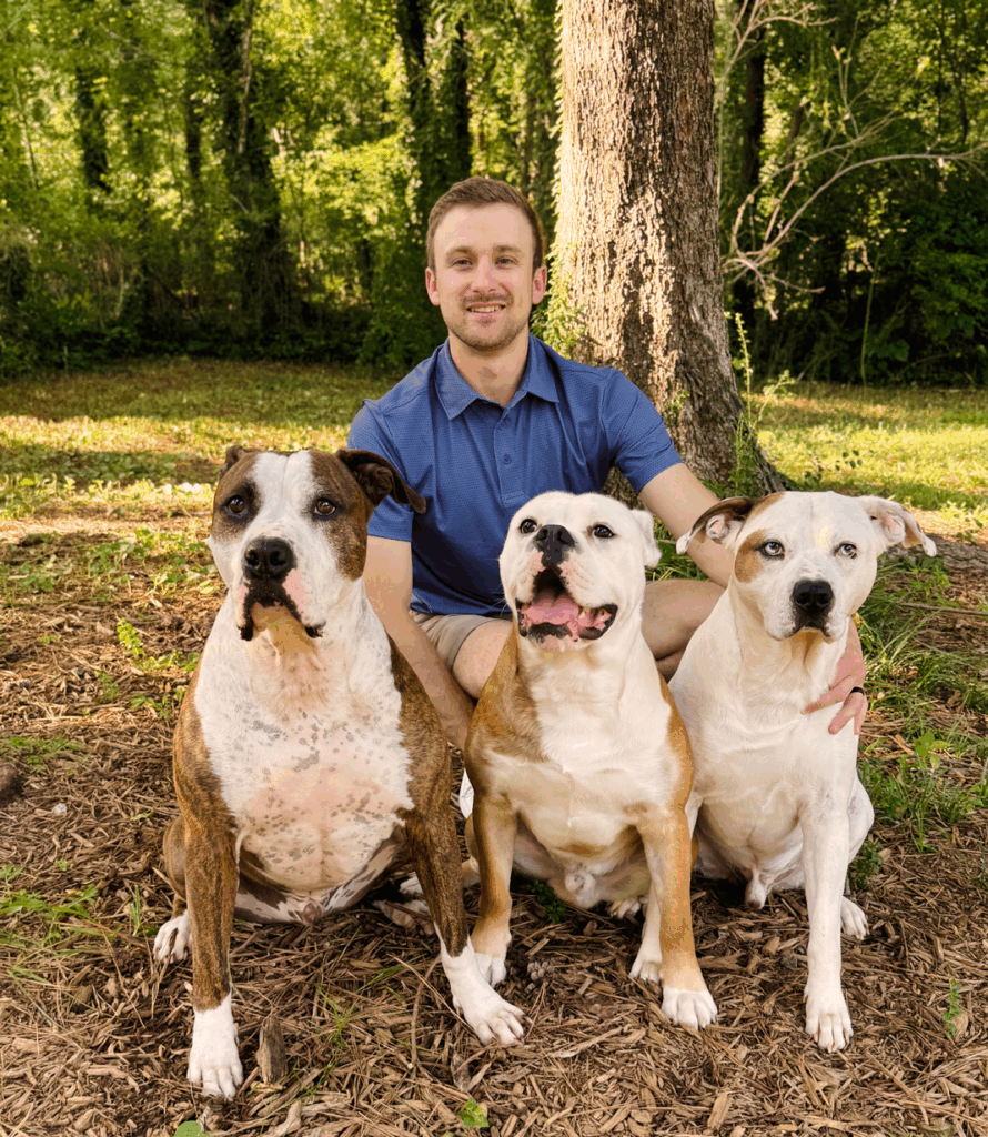 Person with three dogs in a wooded area.