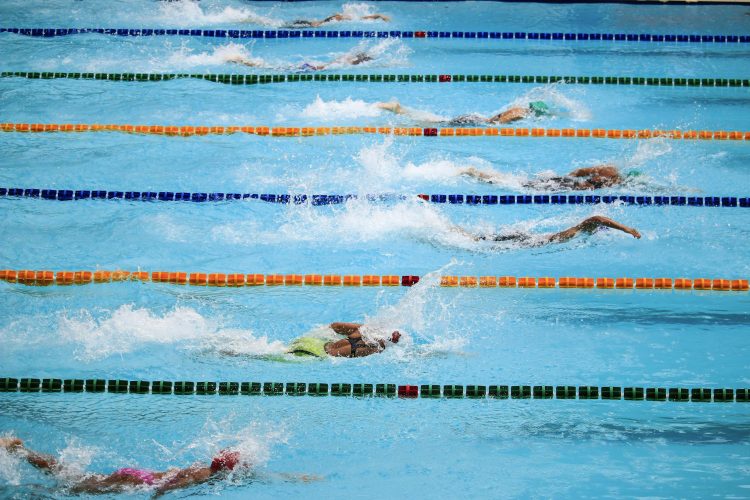 Swimmers compete in an outdoor pool race, showcasing athleticism and sportsmanship.