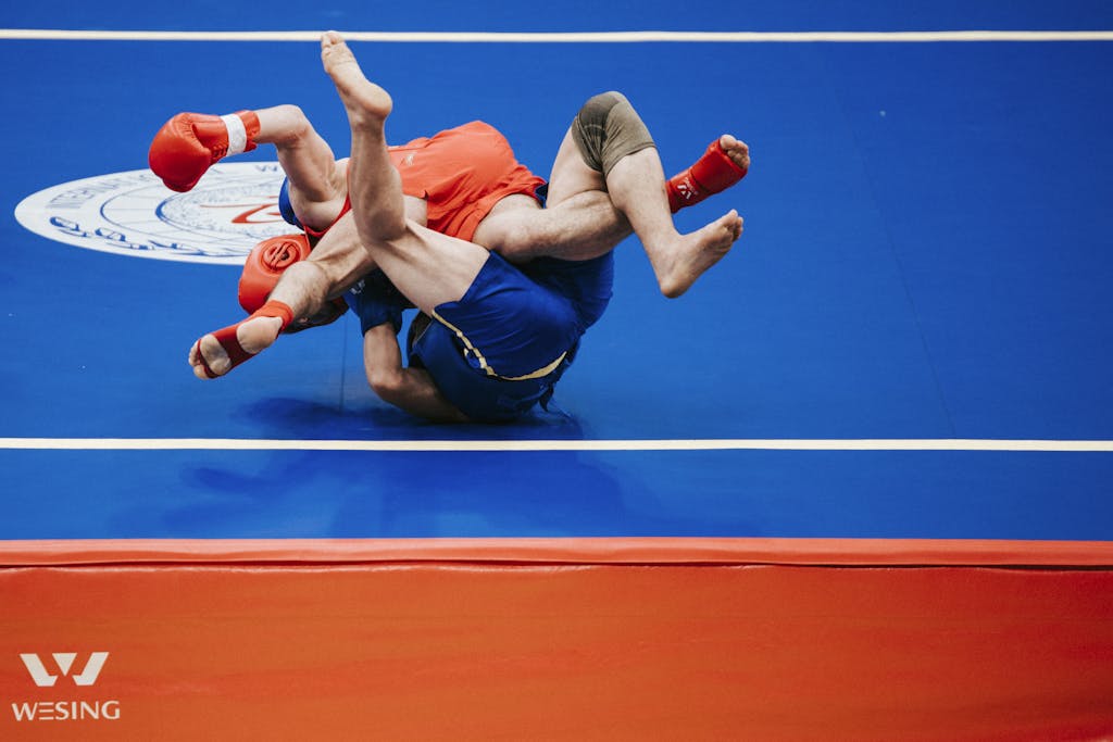 Two athletes engaged in an intense wrestling match on a blue mat.